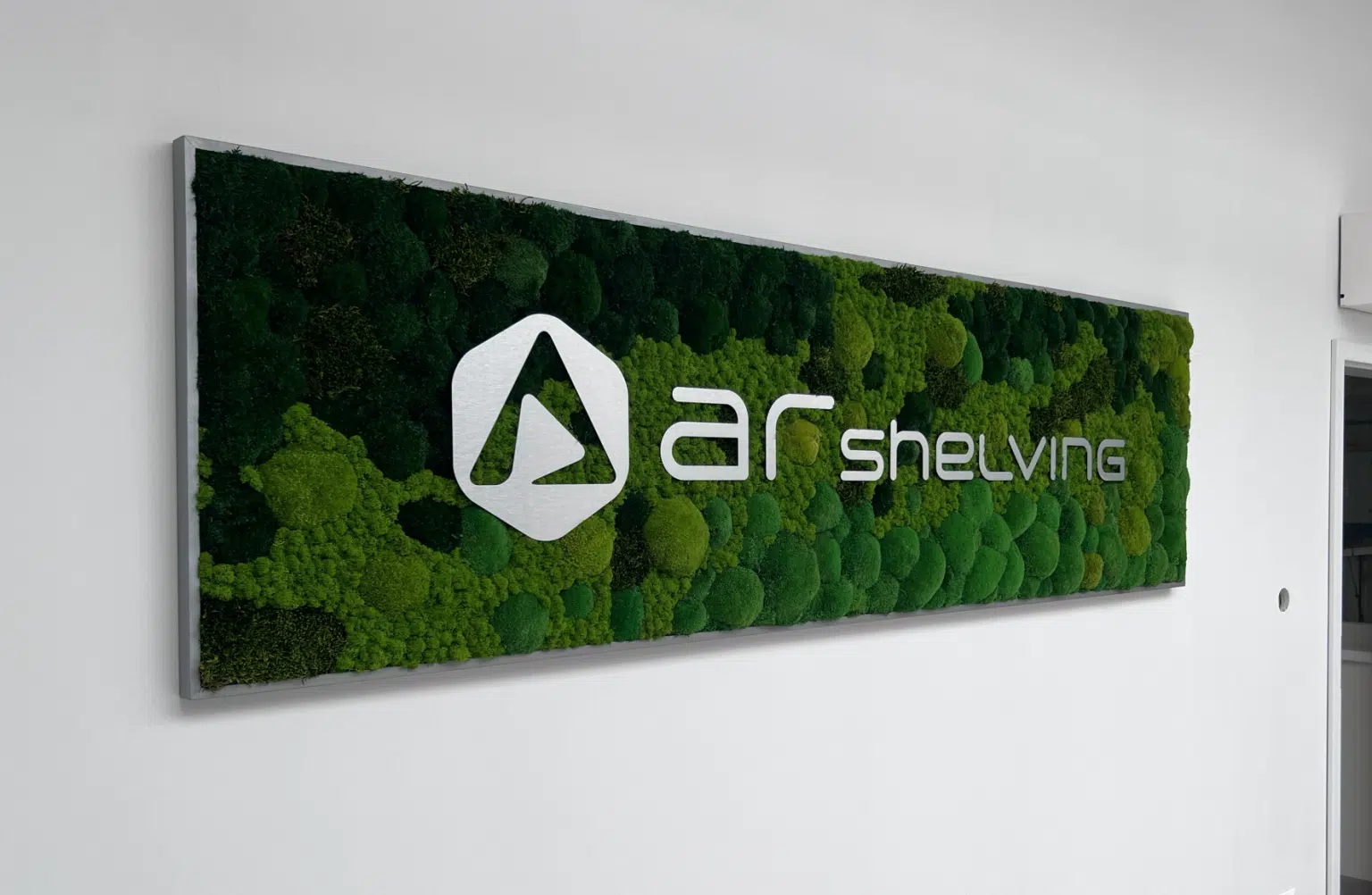 Mechová stěna s bílým logem společnosti AR Shelving